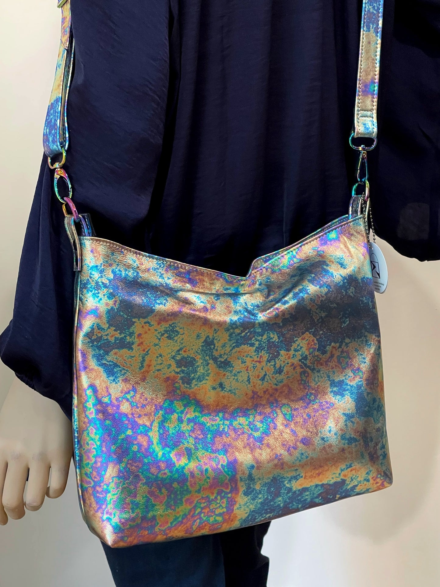 oil slick petrol pattern multi coloured handbag with a person wearing a dark blue silk shirt