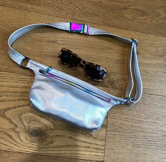 Silver reflective fanny pack with sunglasses on a wooden surface