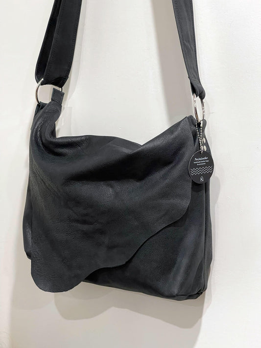 Matte Black bag with asymmetrical flap closure and large O ring strap attachment.