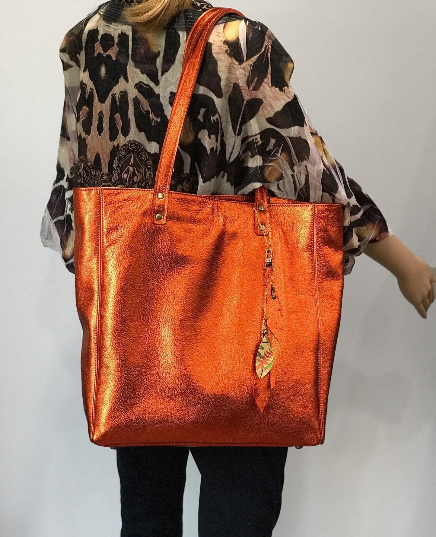 Soft Metallic warm orange leather Tote with strong lining. protective feet and padding. leather zipper pocket and key clasp. Large size on model