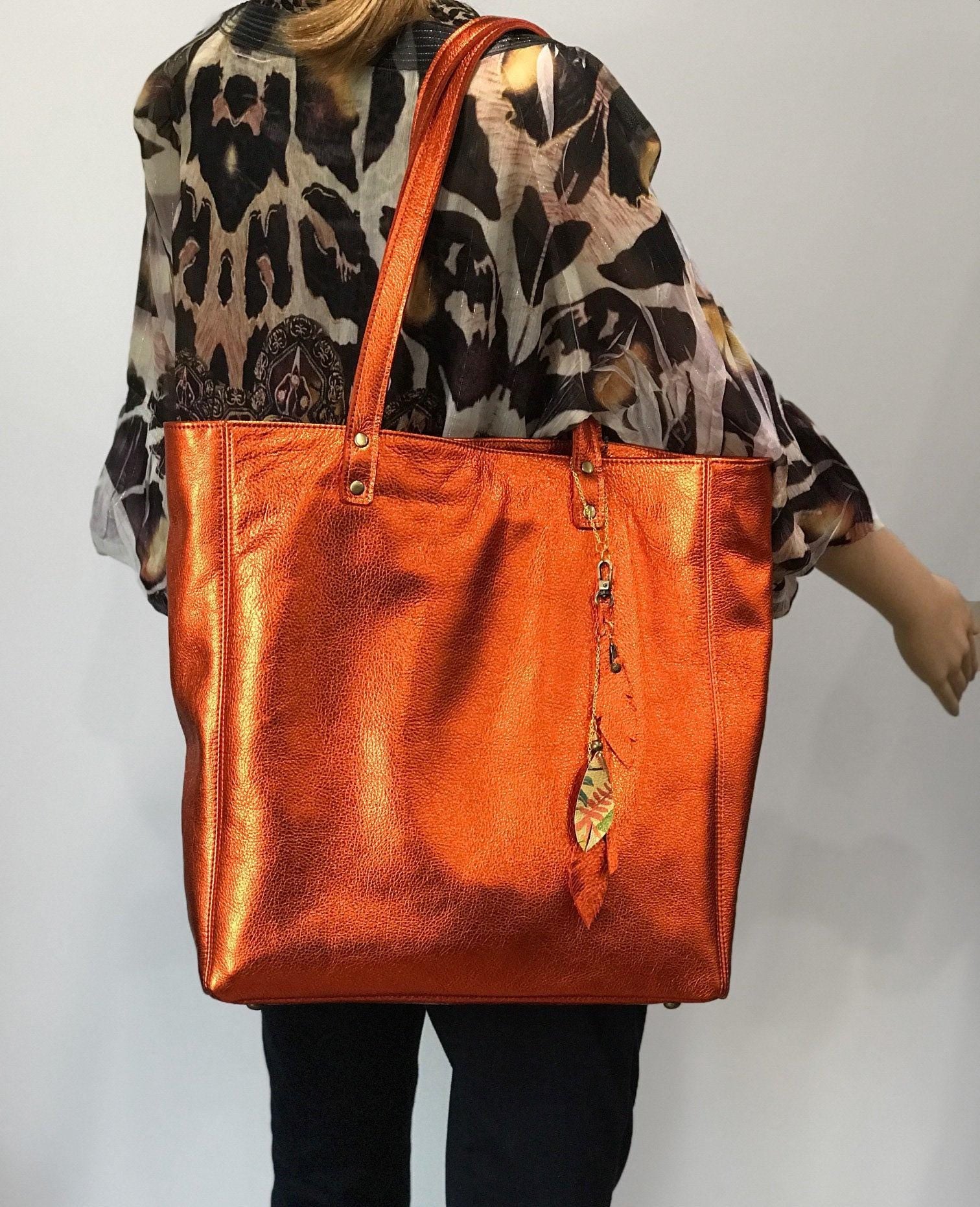 Soft Metallic warm orange leather Tote with strong lining. protective feet and padding. leather zipper pocket and key clasp. Large size on model