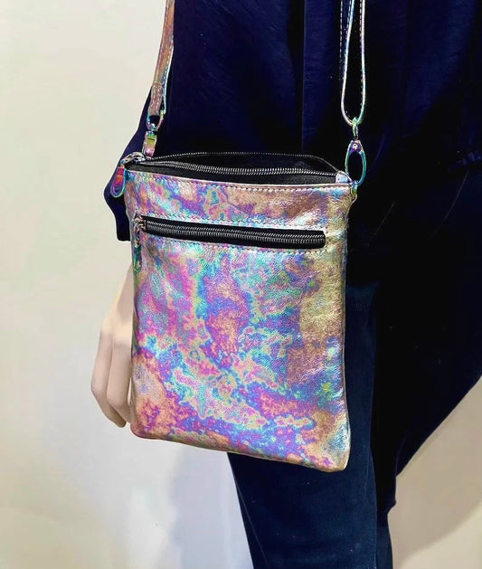 Multi colour Oil Spill crossbody bag held by a person against a neutral background. top zipper closure