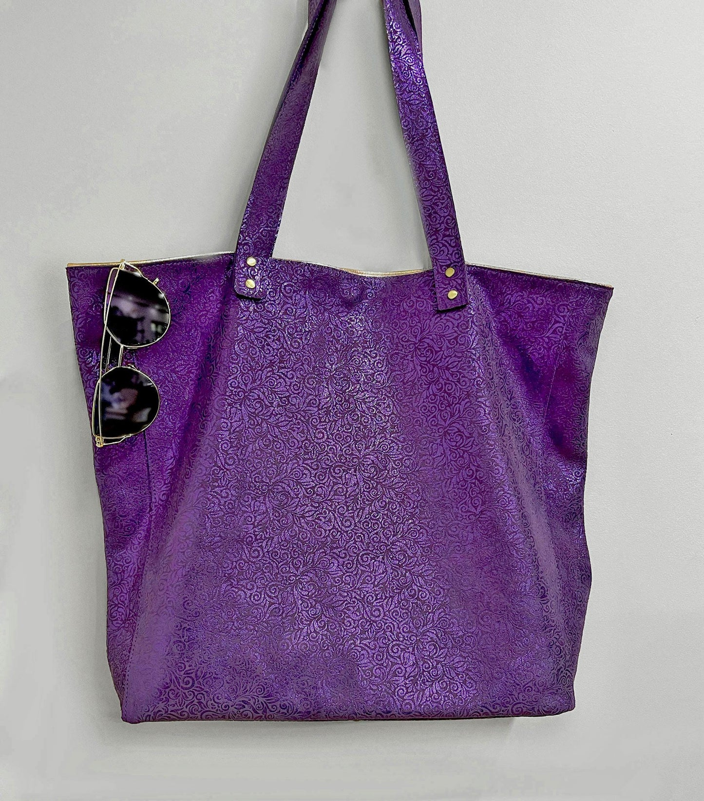 Purple tote bag with sunglasses on a light gray background. metallic small floral print on suede