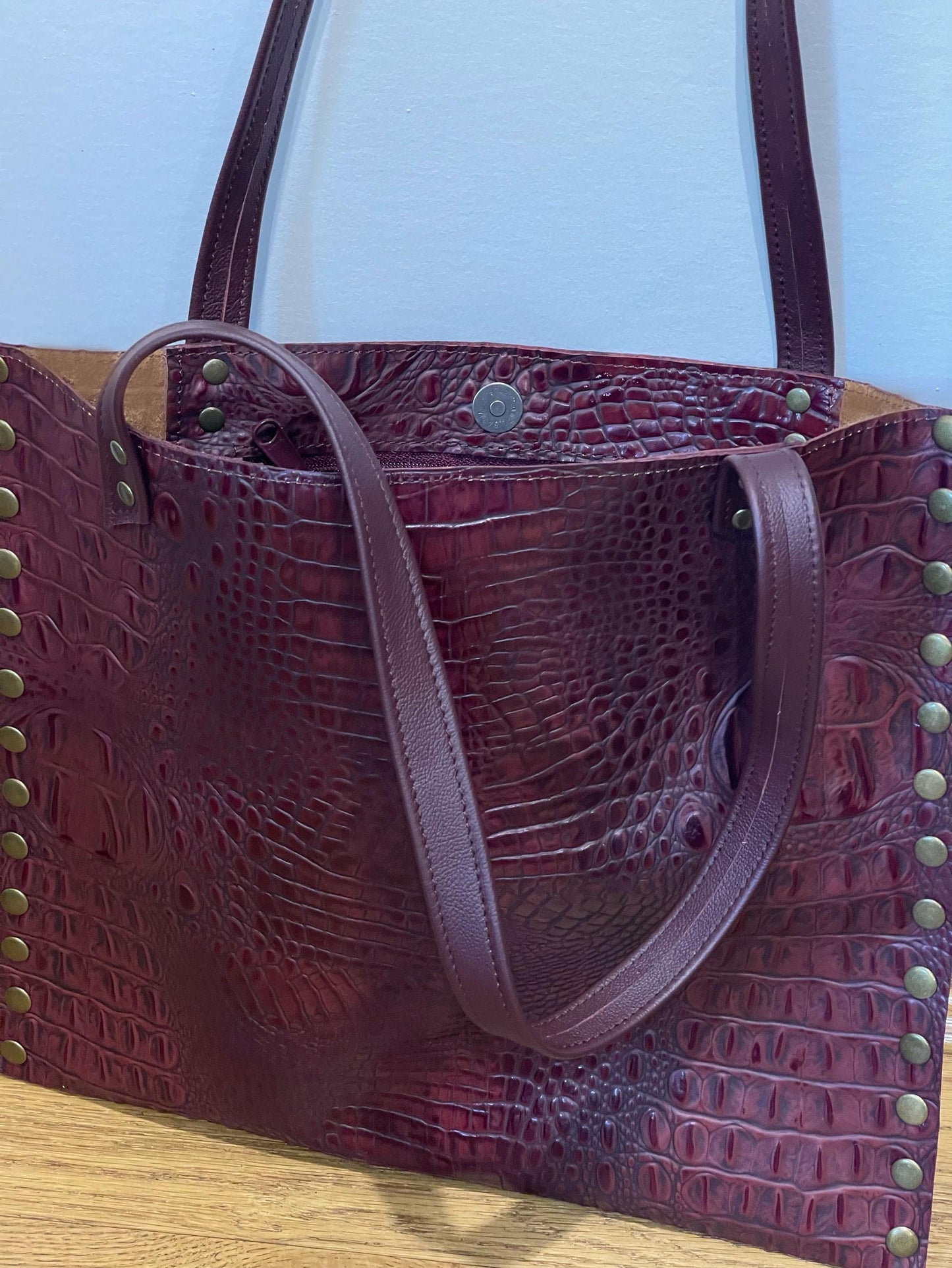 Maroon textured handbag with gold studs and inside zipper pocket with magnet closure