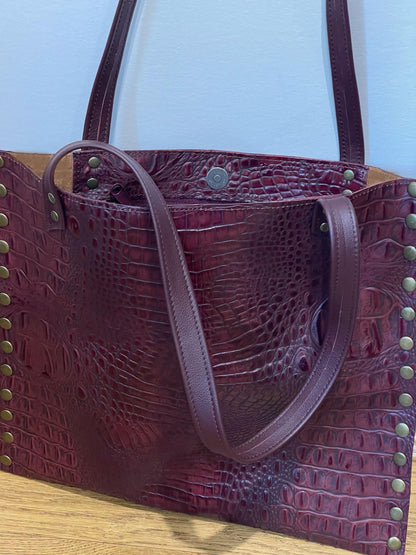 Maroon textured handbag with gold studs and inside zipper pocket with magnet closure