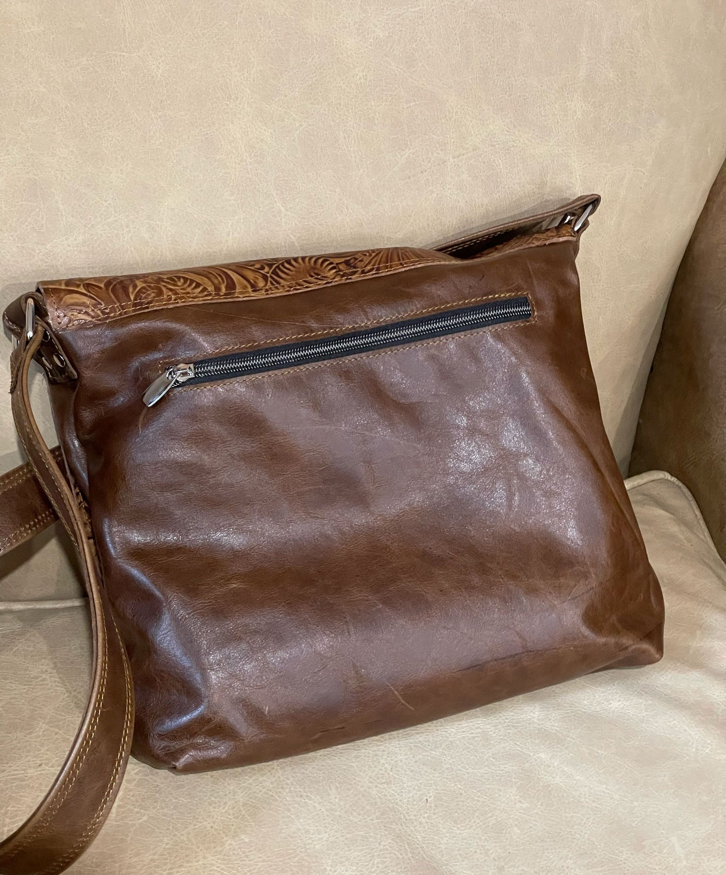 Brown leather handbag with a visible outside zipper on the back of the bag