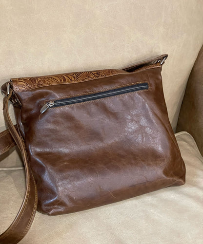 Brown leather handbag with a visible outside zipper on the back of the bag