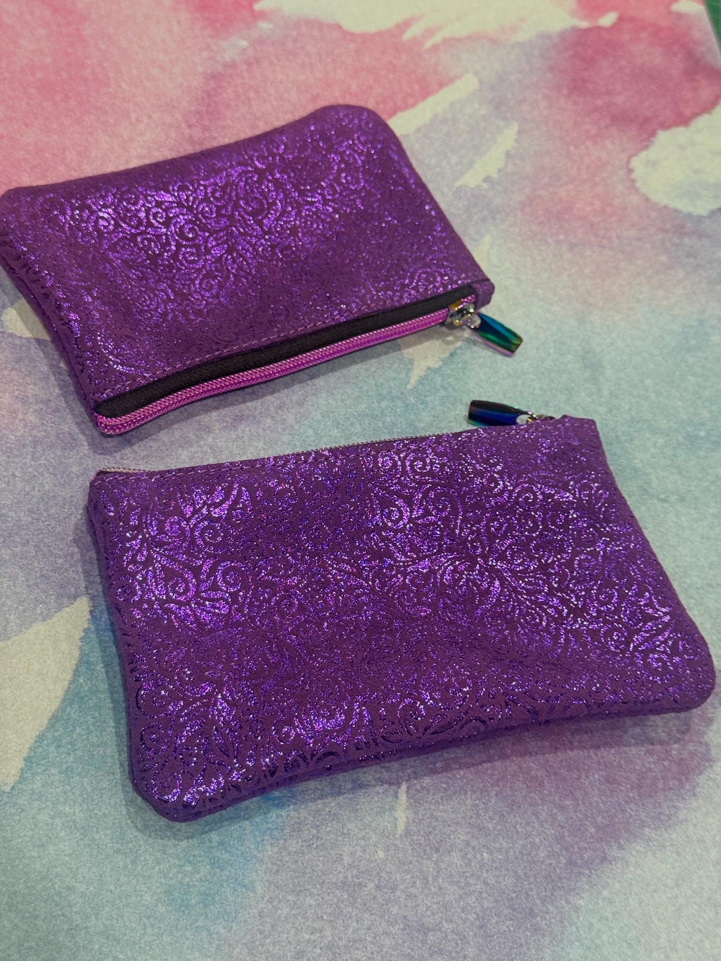 Two purple glittery pouches on a colorful background
