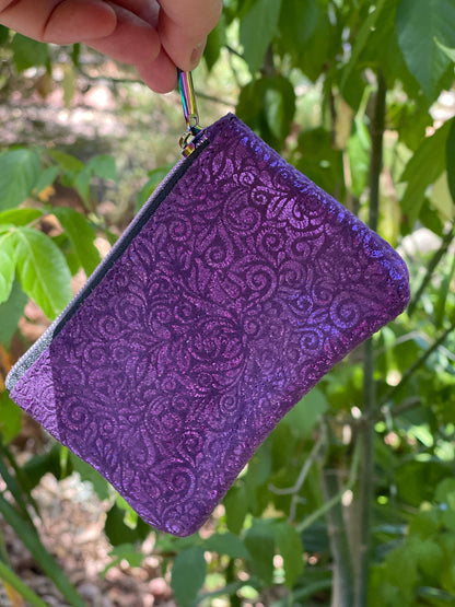 Purple textured pouch held in front of green foliage