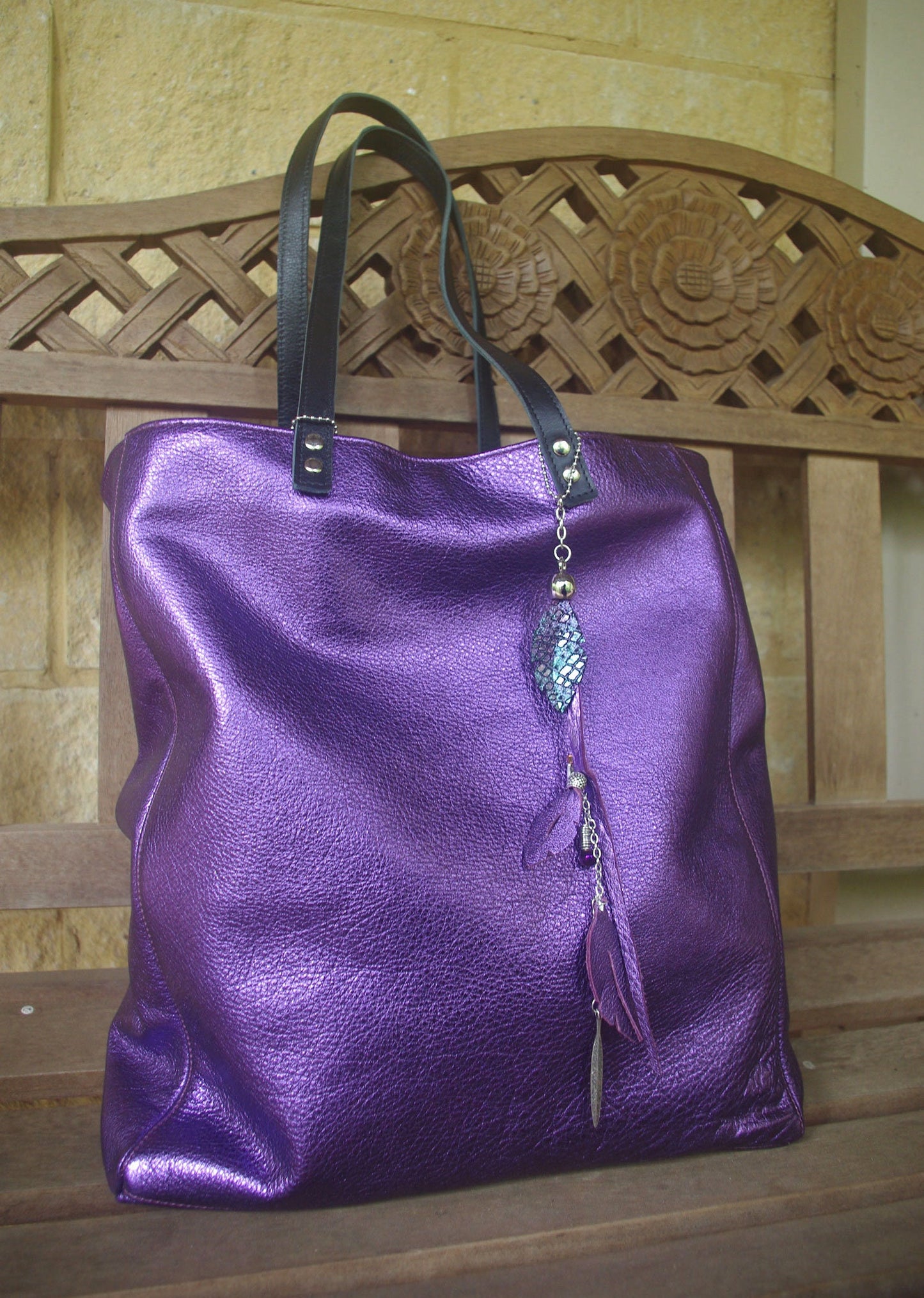 Purple handbag with decorative elements on a wooden bench