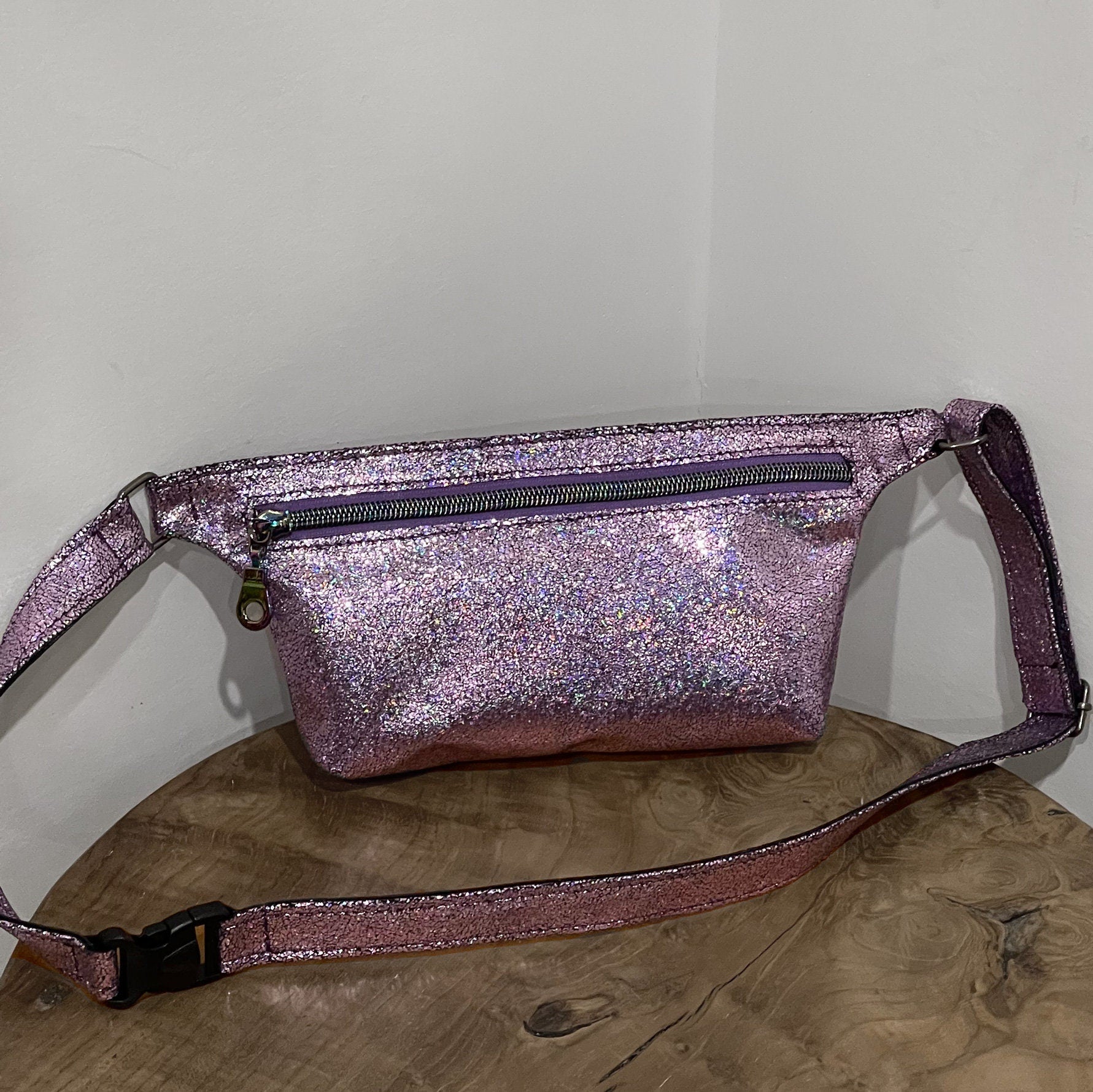 Glittery pink fanny pack on a wooden surface with a white background