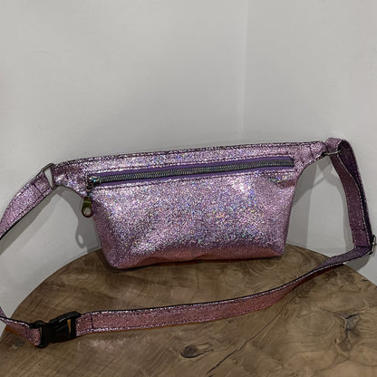 Glittery pink fanny pack on a wooden surface with a white background