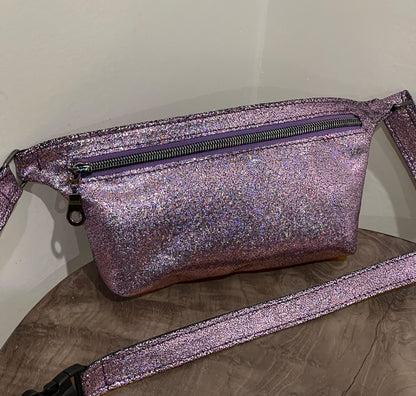 Pink glittery fanny pack waist bag on a wooden surface with a neutral background