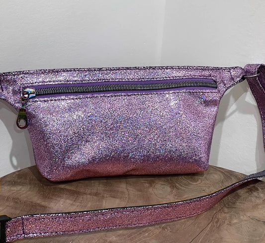 Glittery pink waist bag on a wooden surface with a plain background