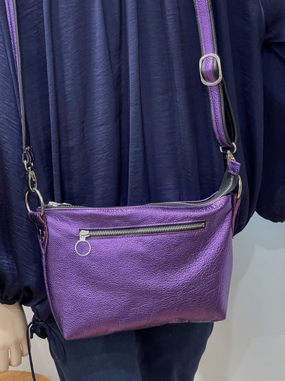 Purple metallic leather handbag with silver hardware  and removable strap and outside pocket worn by a person