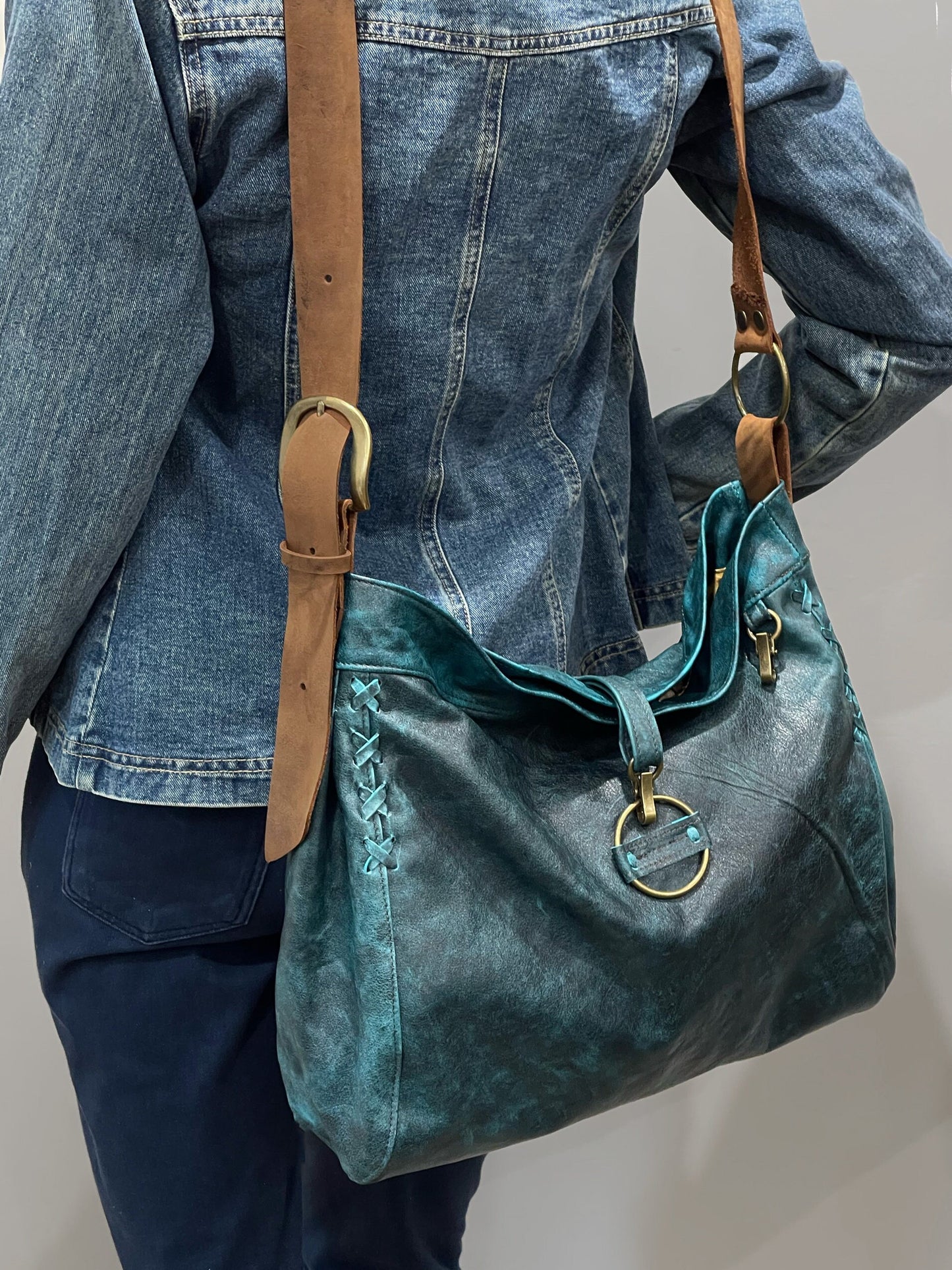 Vintage teal green boheme handbag with brown strap worn by a person wearing denim