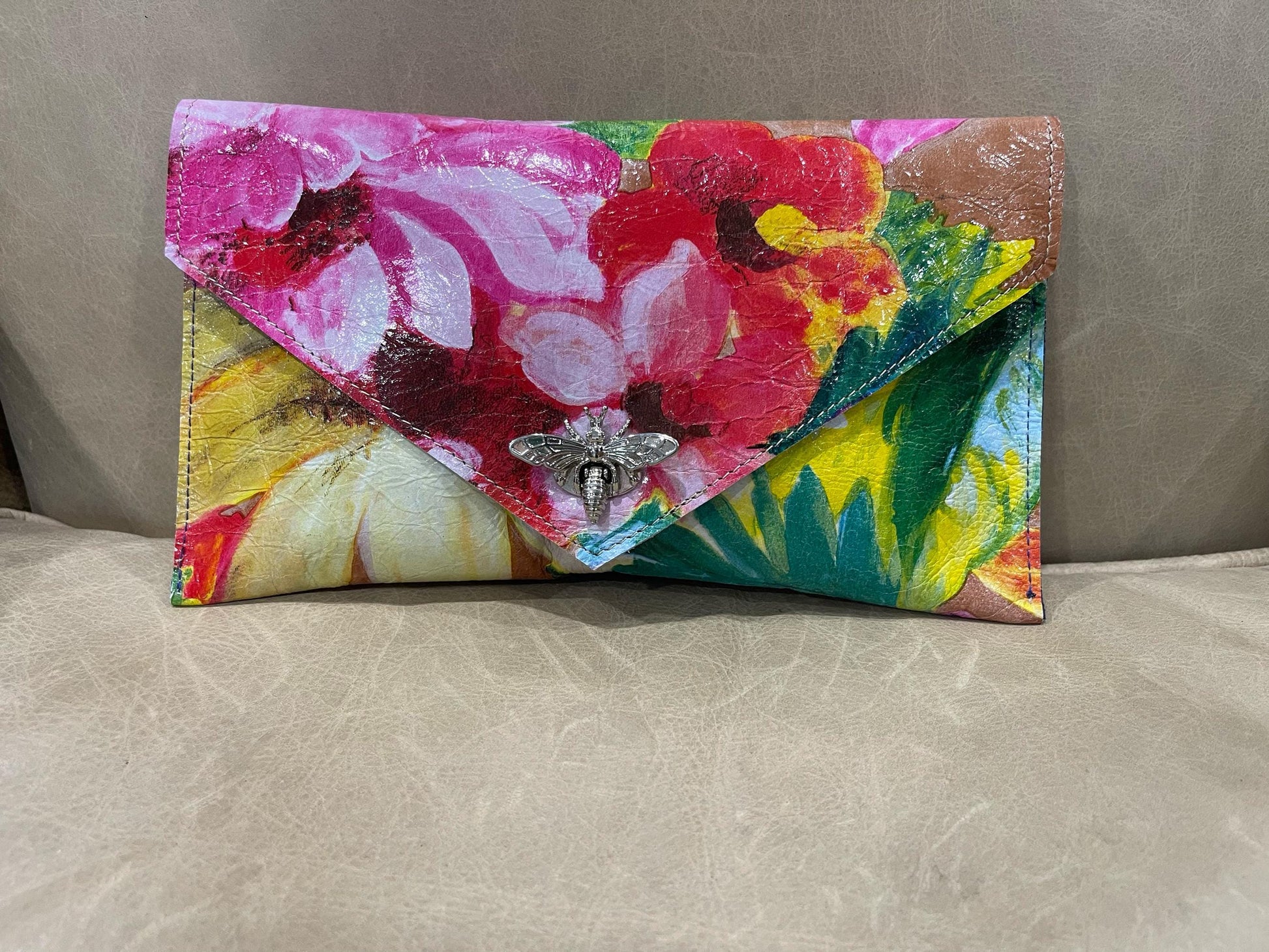 Colorful floral-patterned clutch bag on a beige surface