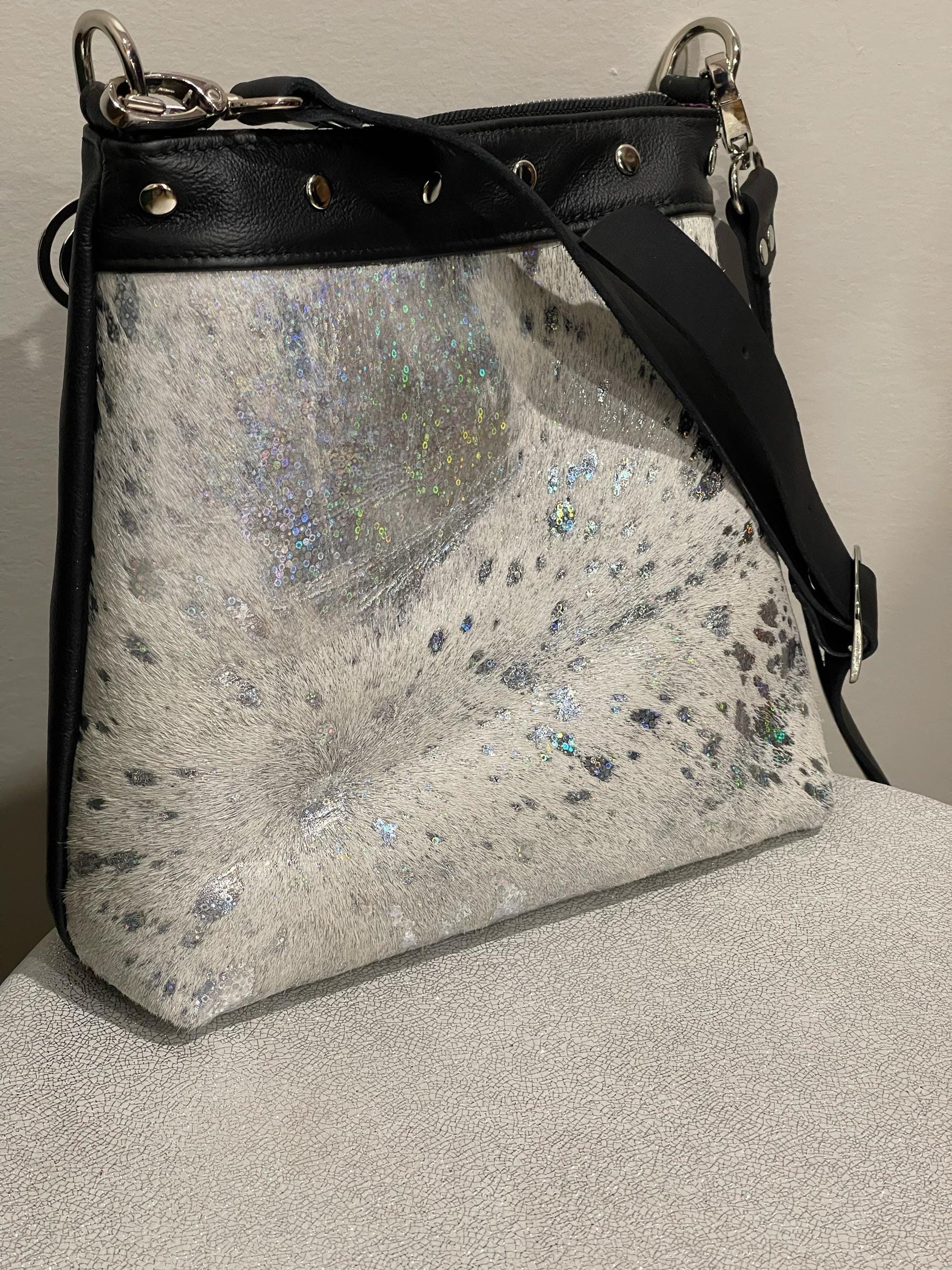 holo acid washed white cowhide bag and black accents on a neutral background