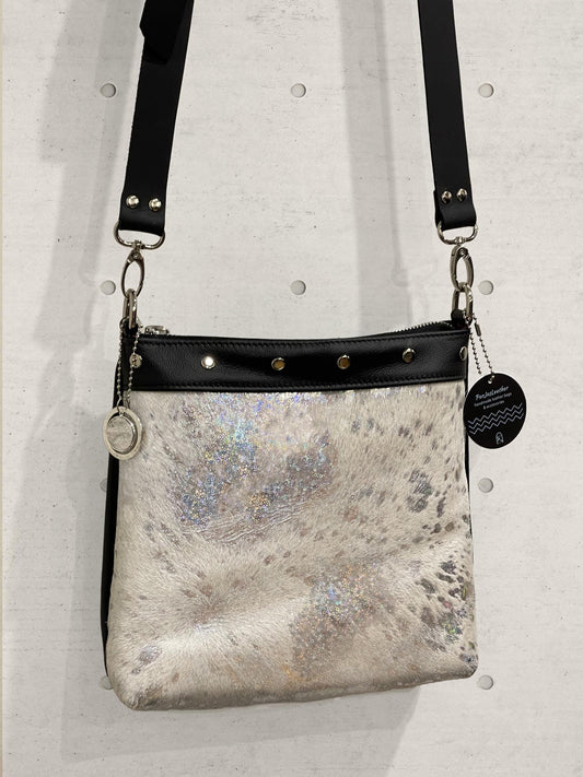 Silver metallic handbag with black strap on a light gray background