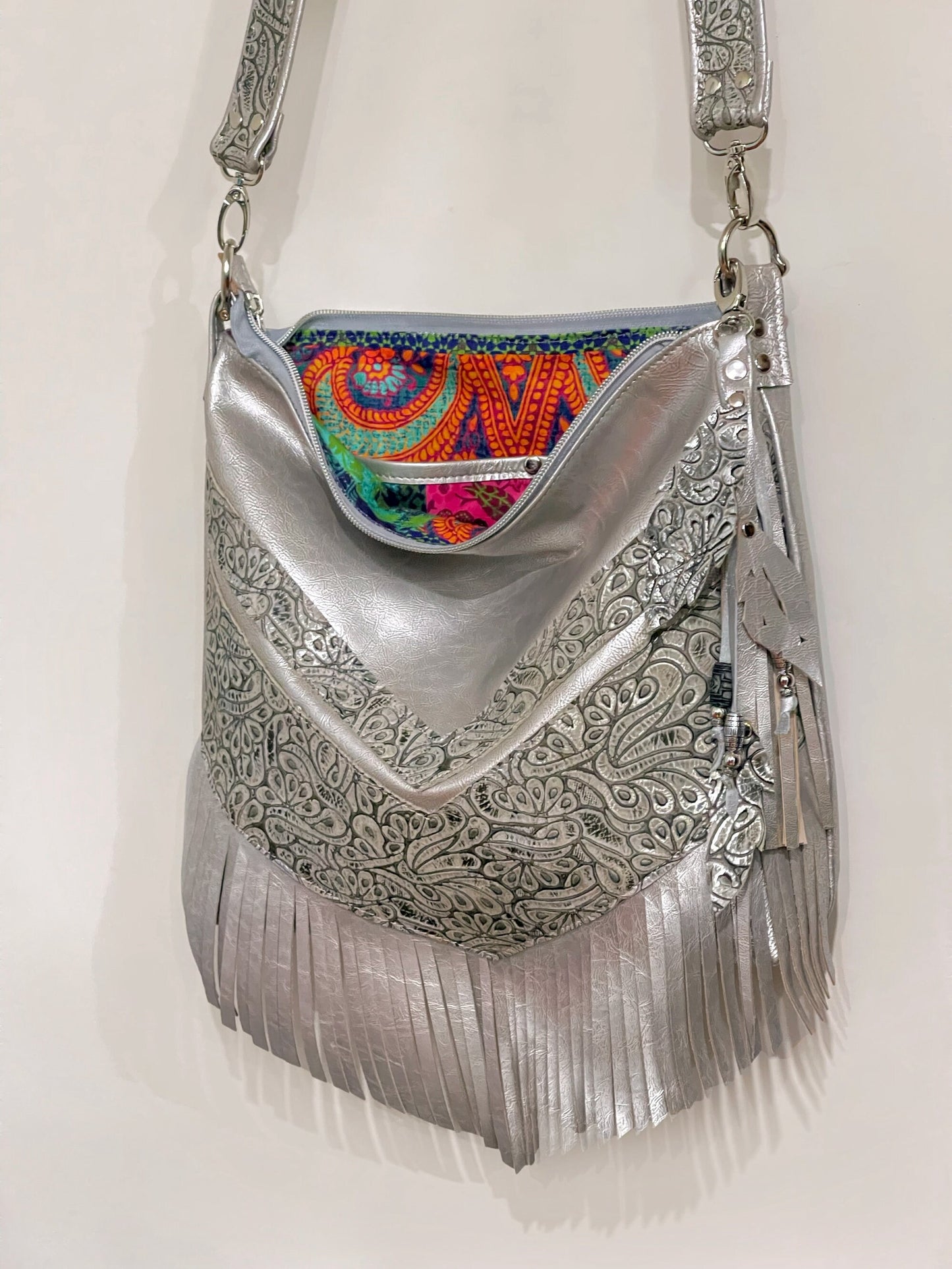 Silver handbag with intricate patterns and colorful beaded leather charm and boho colourful lining