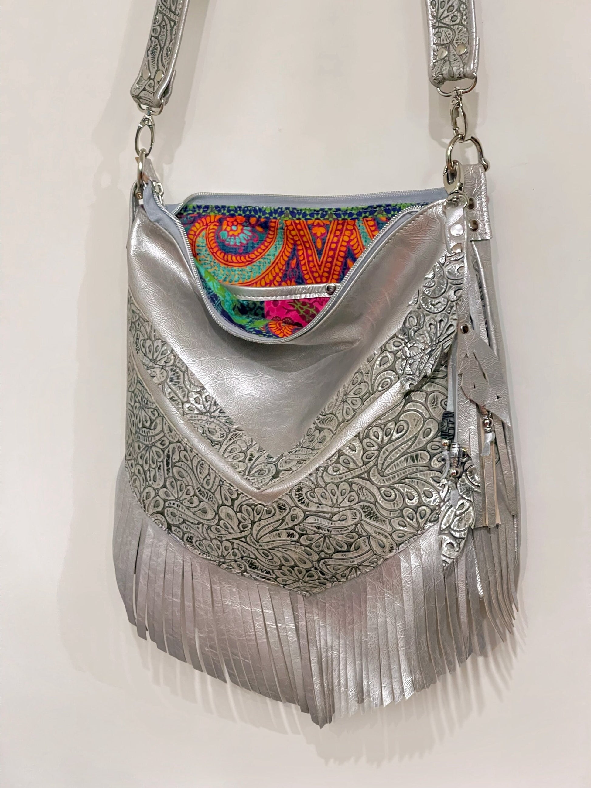 Silver handbag with intricate patterns and colorful beaded leather charm and boho colourful lining