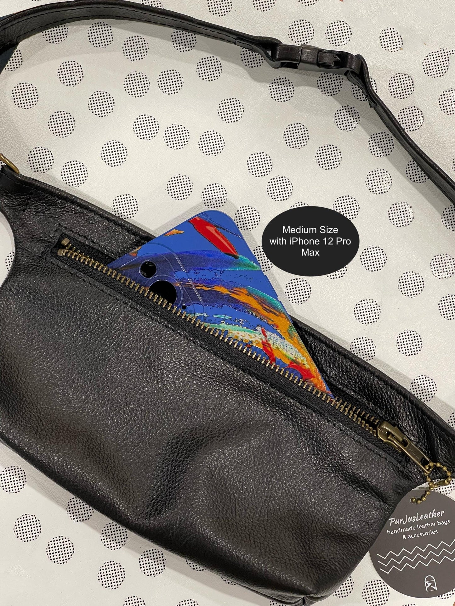 Black leather fanny pack with colorful phone case on a polka dot background