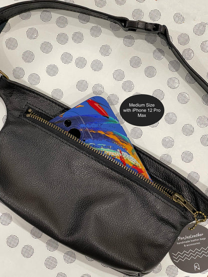 Black leather fanny pack with colorful phone case on a polka dot background