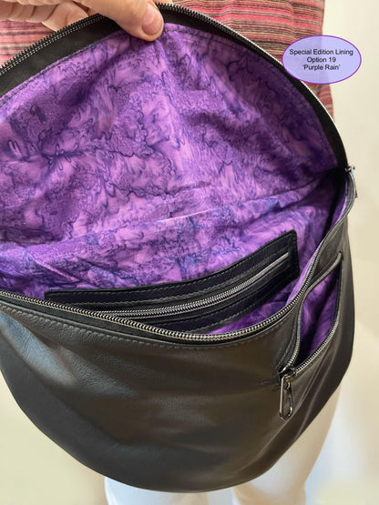Black bag with purple tie dye lining on a mannequin, labeled 'Special Edition Lining Option 19 Purple Rain'. showing inside and outside  zipper pockets.