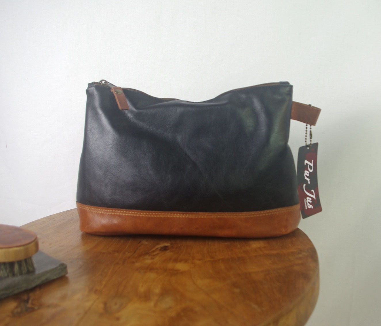 Black and brown handbag on a wooden surface with a visible tag.