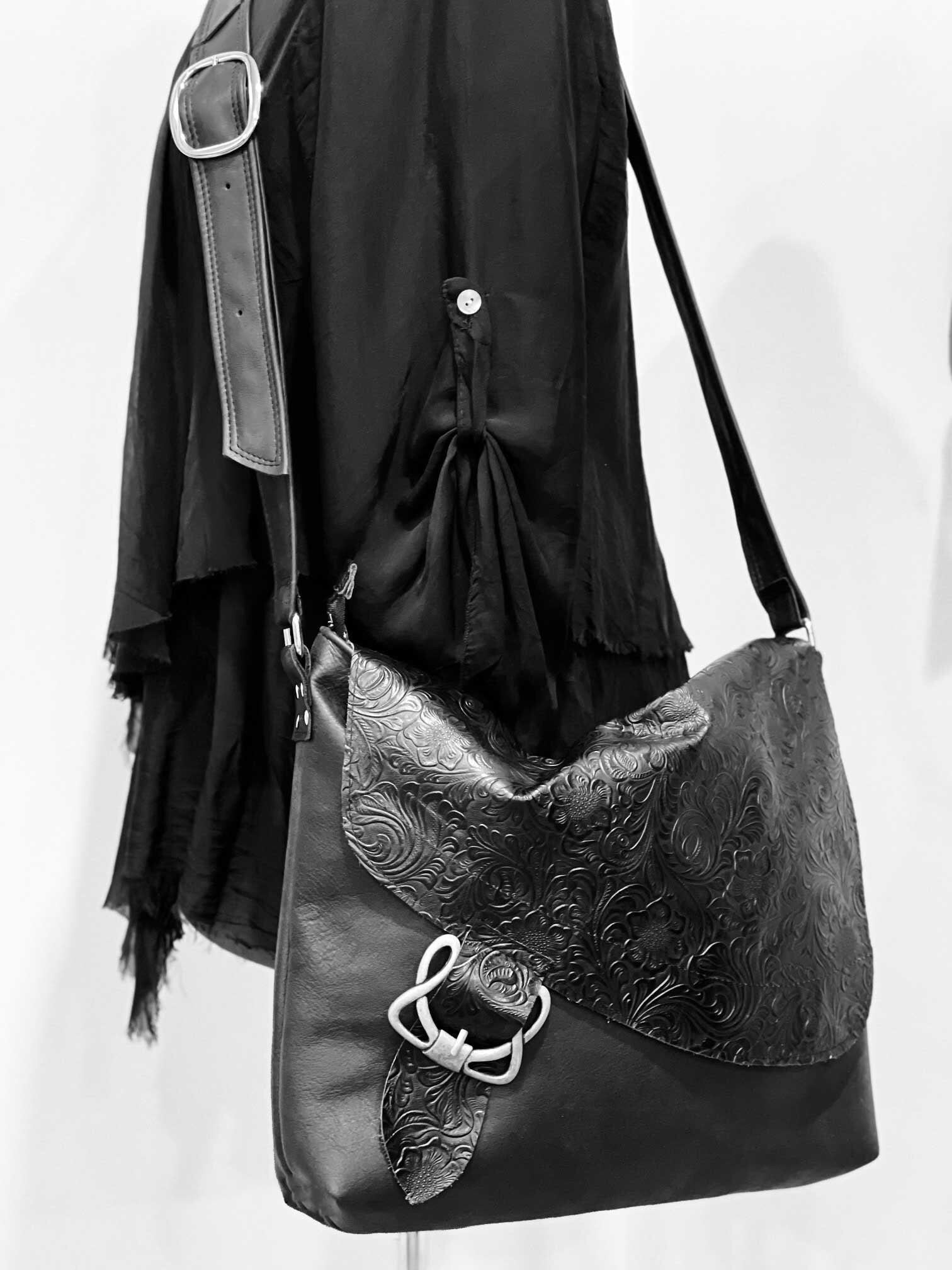 Black leather handbag with intricate design and silver buckle on a white background