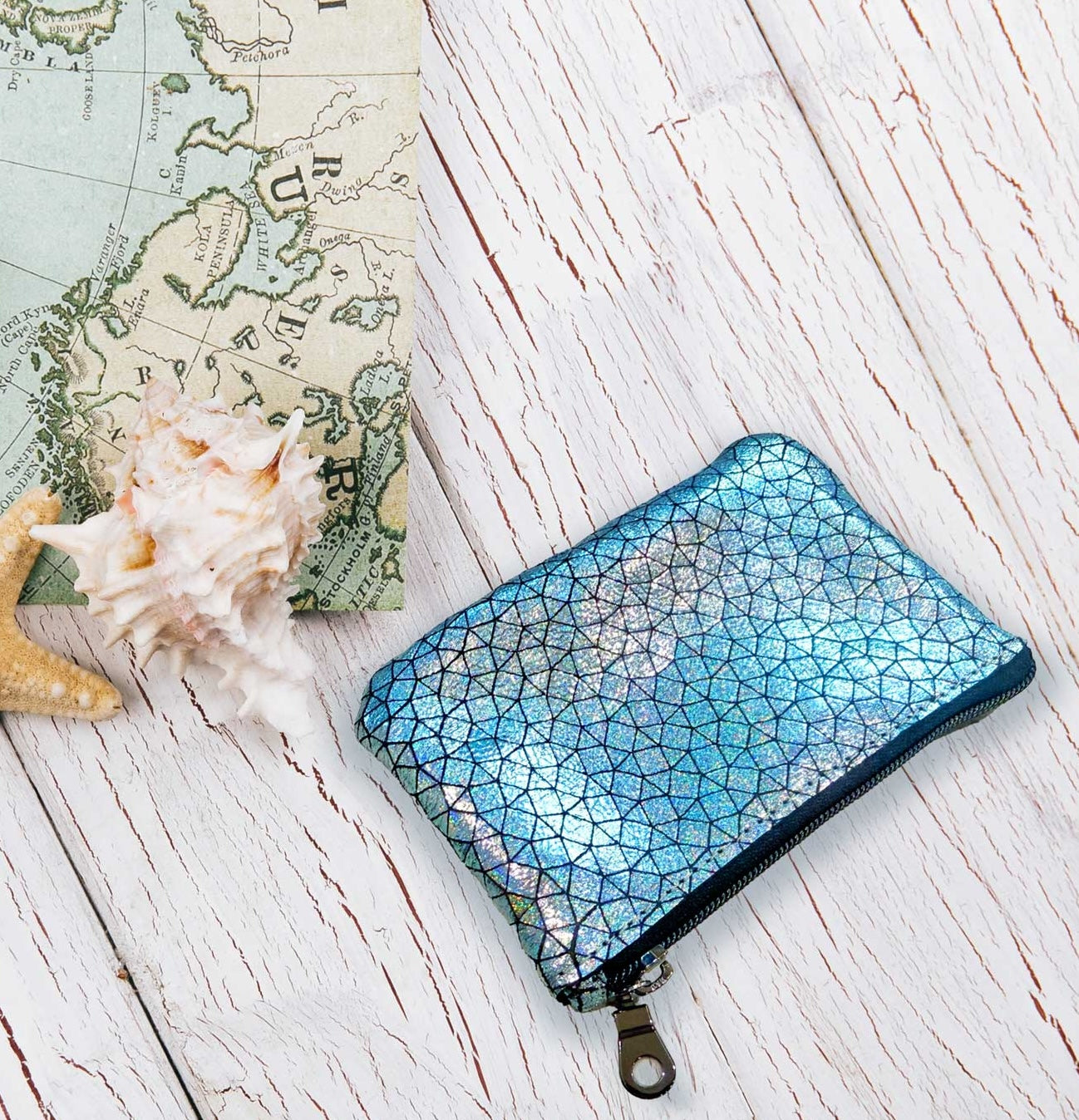 Blue geometric patterned holographic zipper pouch in a travel beach scene