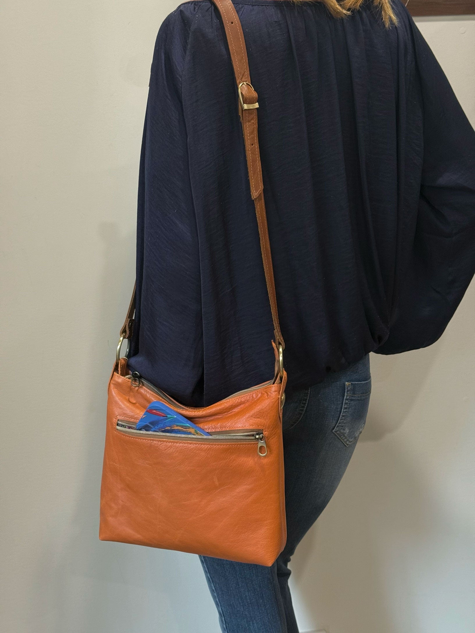 warm tan leather crossbody bag with zipper pocket on model