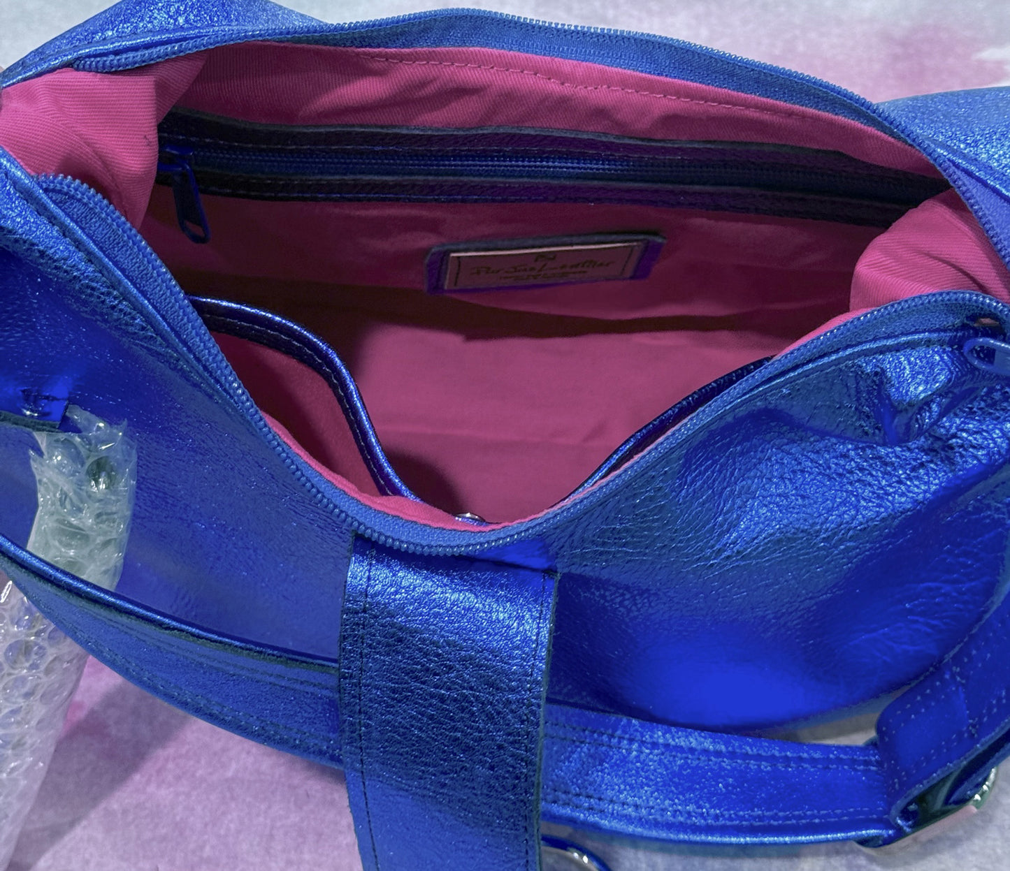 Blue handbag with pink interior lining zipper pocket and slip pocket for easy access