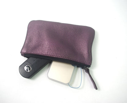 Purple leather pouch containing a car key and phone on a white background