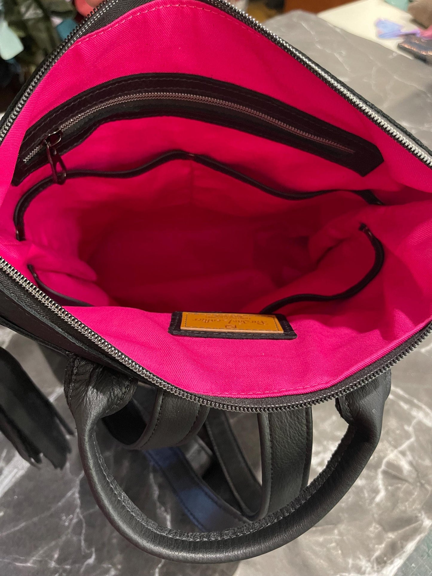 backpack showing inside lining of hot pink and zipper pocket and multiple slip pockets