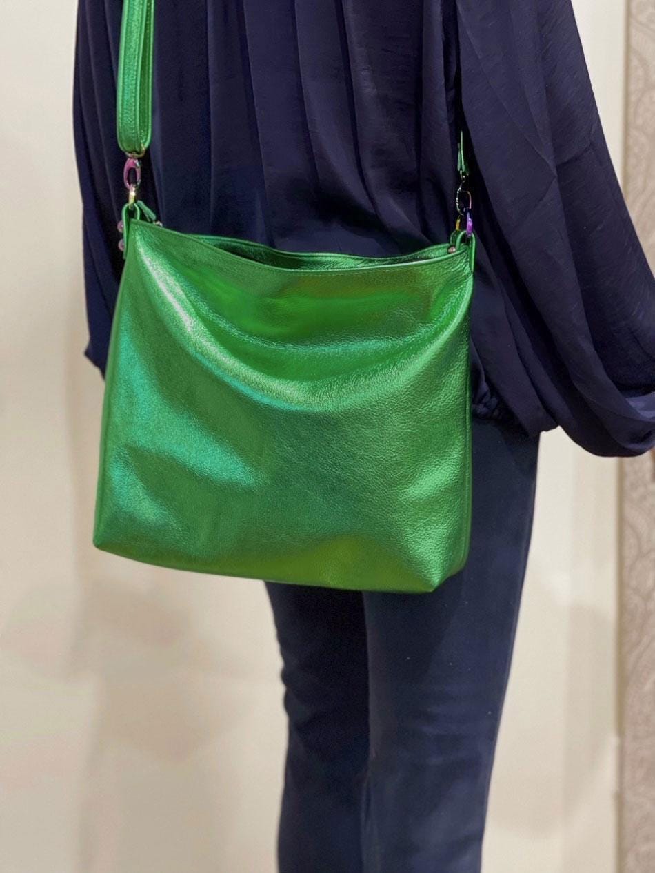 Green handbag worn over one shoulder against a neutral background