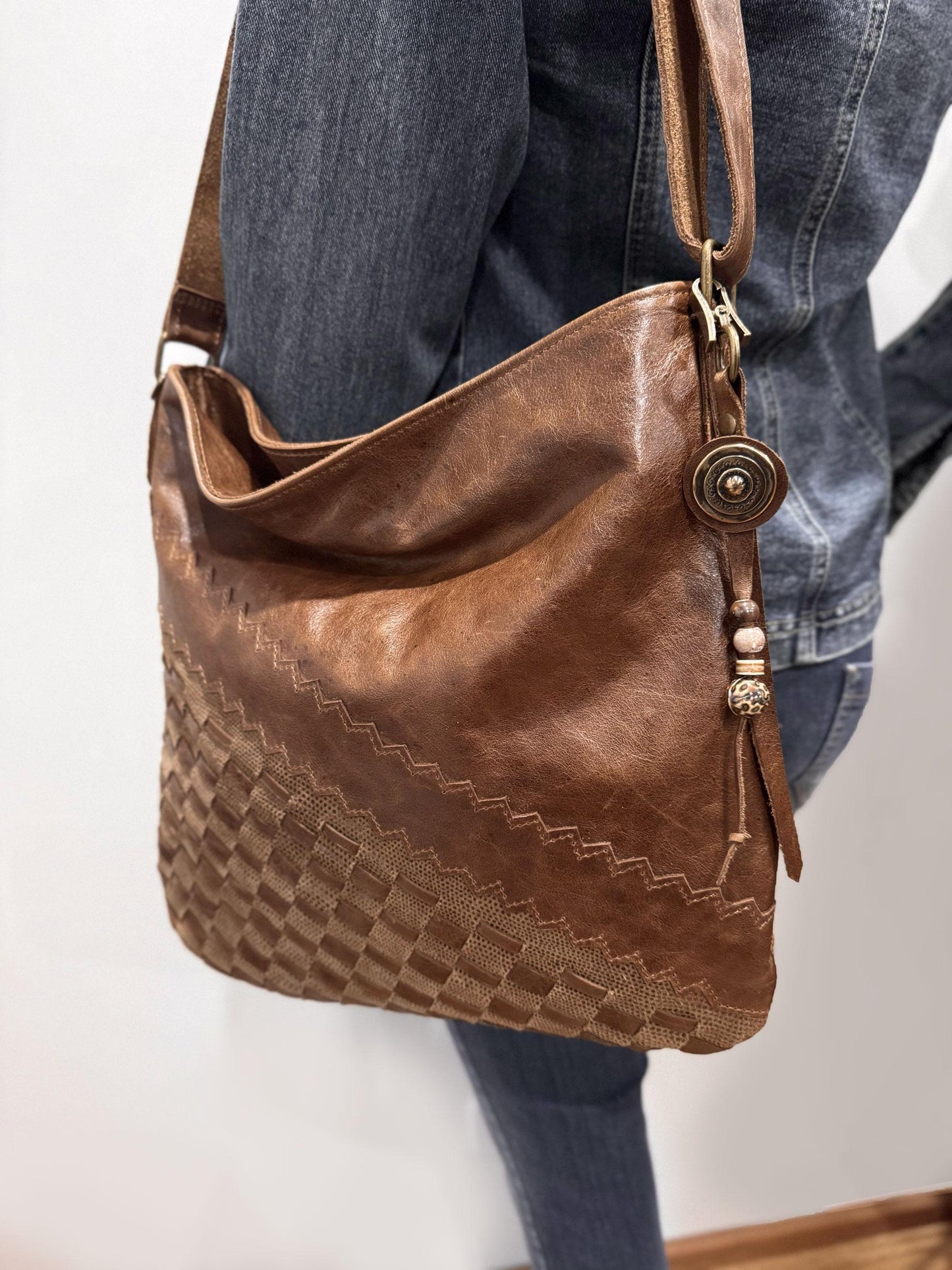 model wearing denim with Brown leather handbag with decorative stitching and concho