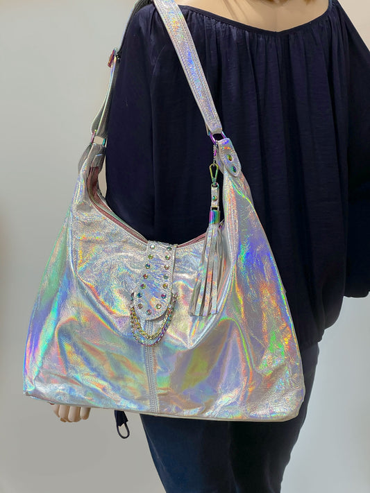 model wears Holographic hobo handbag with a wide strap and studded chain feature and detachable leather fringe