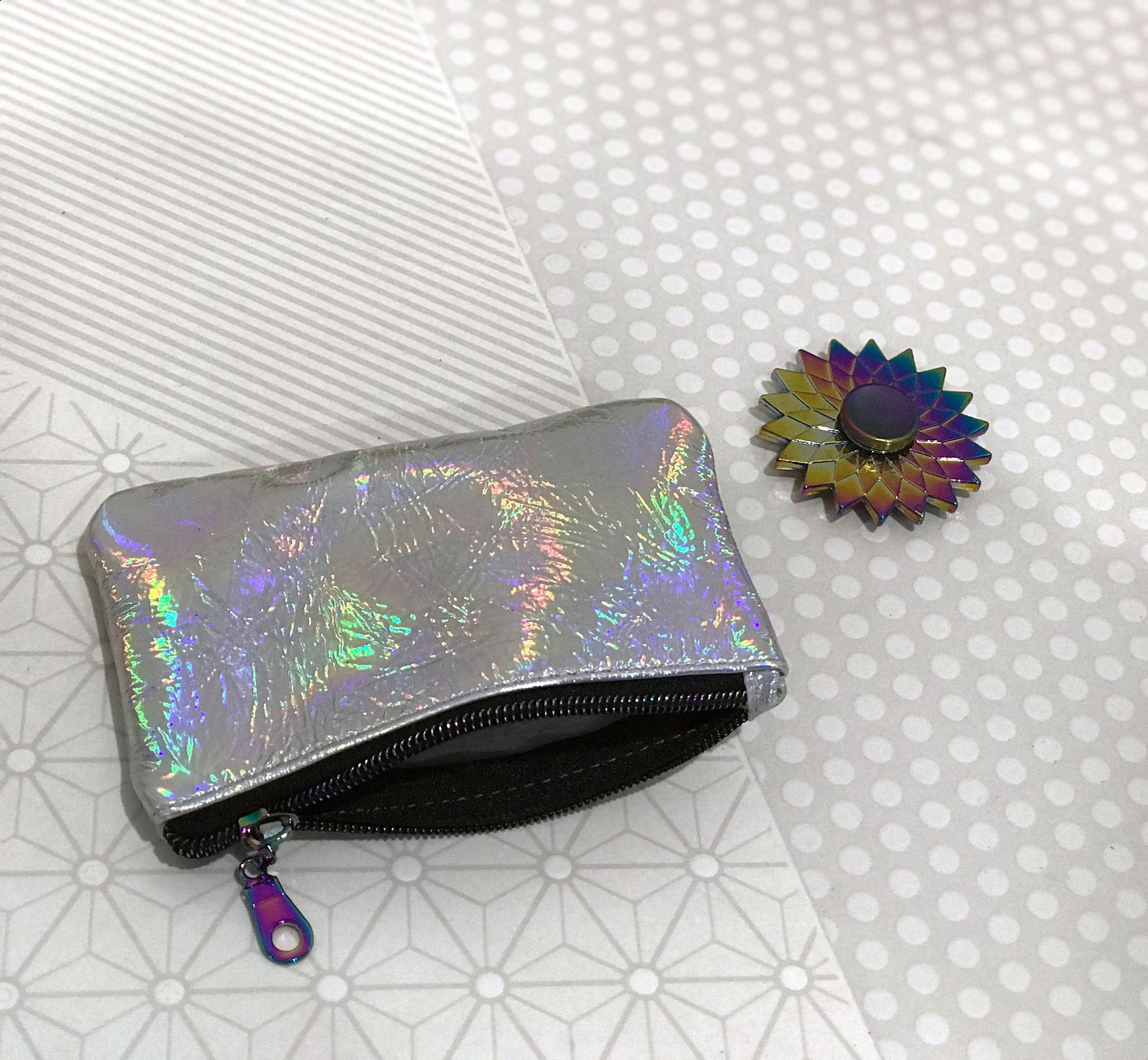 Holographic pouch and colorful flower-shaped object on a patterned surface