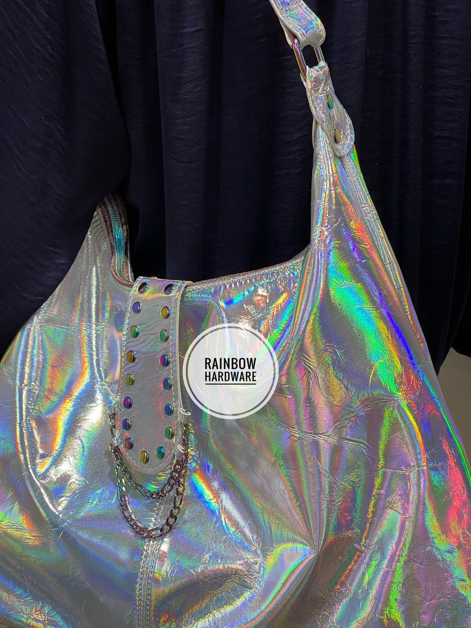 close up of Holographic handbag with 'Rainbow Hardware' and unique rivet chain feature on a dark background