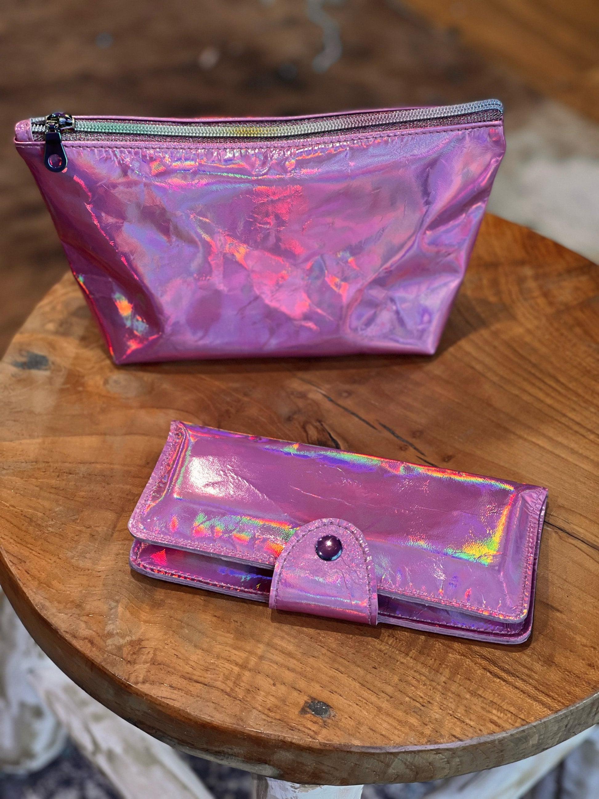 Holographic pink pouch and wallet on a wooden surface