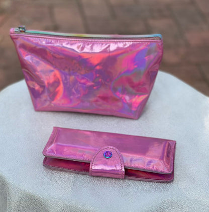 Pink iridescent pouch and wallet on a textured surface with a blurred background