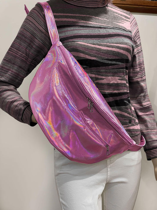 Person wearing a holographic pink bag over one shoulder against a plain background