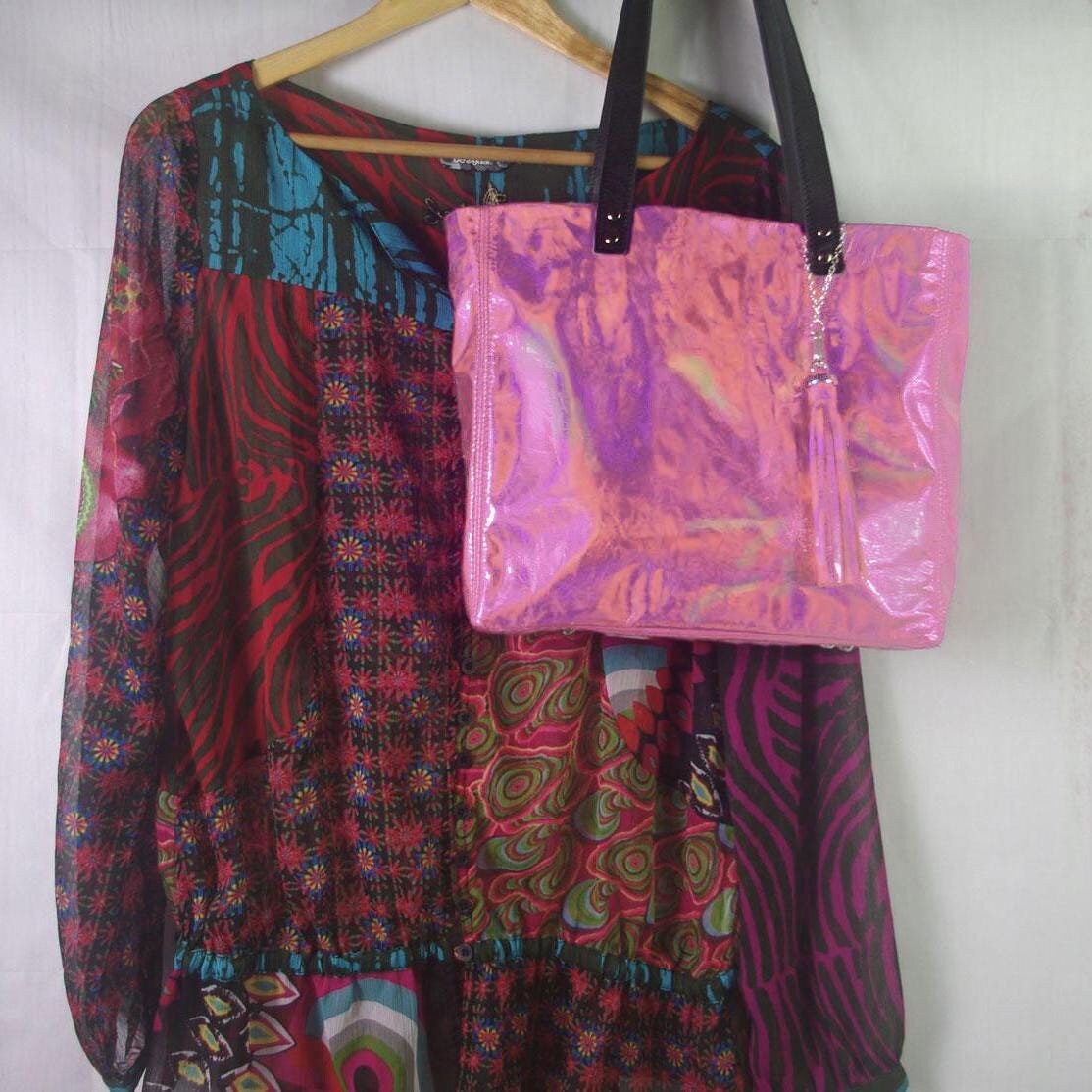 Colorful patterned shirt and pink tote bag on a hanger against a white background