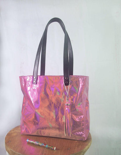 Holographic pink handbag on a wooden stool with a white background