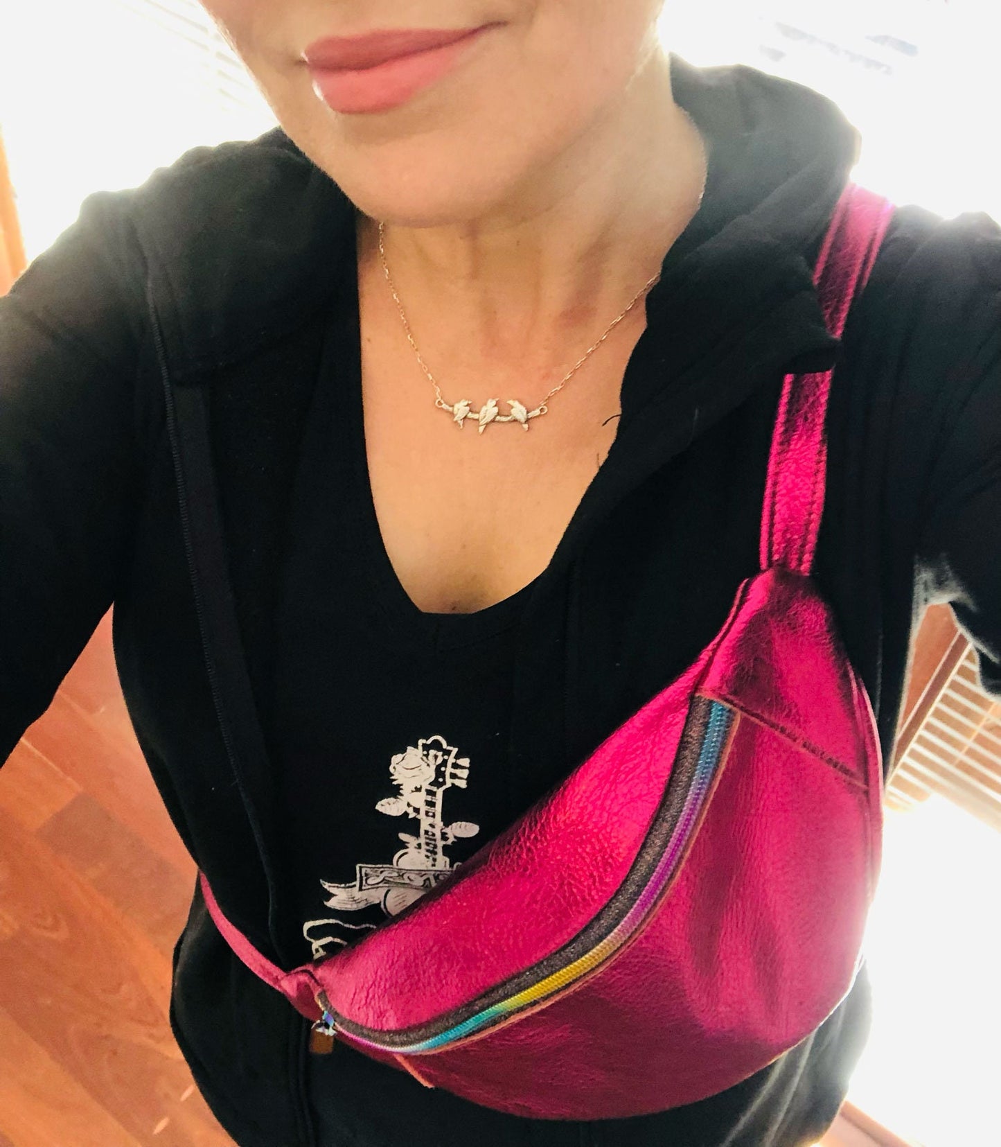 Person wearing a black top with a hot pink metallic bum bag sling crossbody style
