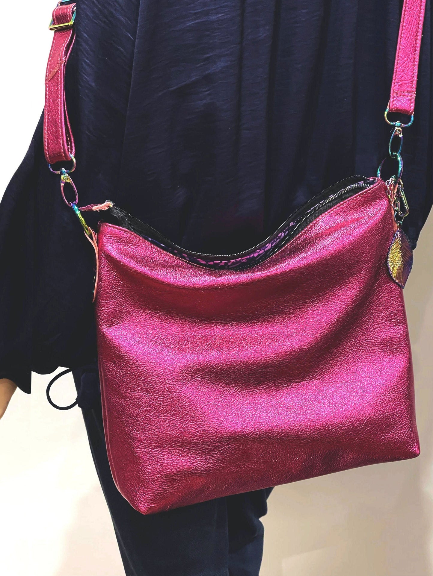 Pink handbag with colorful straps held by a person wearing a dark shirt.