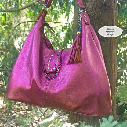 metallic hot pink hobo handbag with rainbow hardware and tassel on a chain hanging on a tree branch