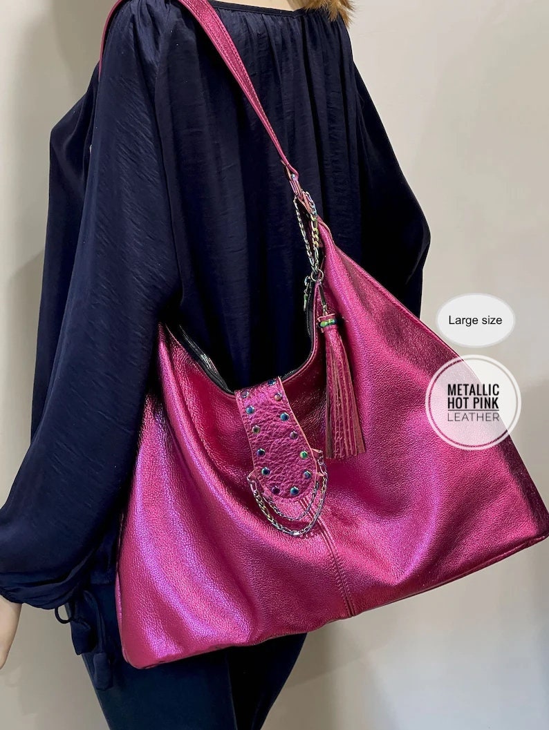 Person holding a pink metallic handbag with a tassel, wearing a navy blue outfit.