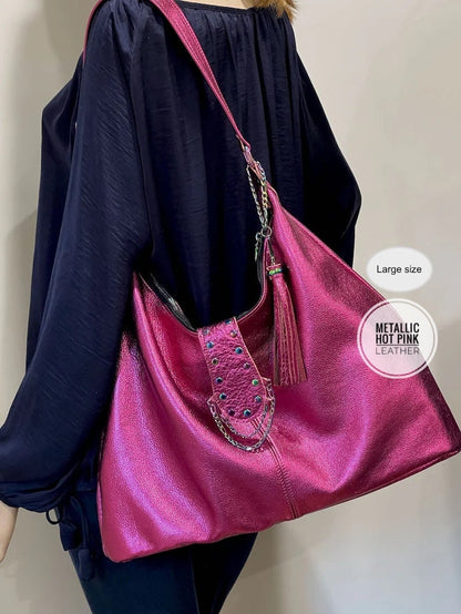 Person holding a pink metallic handbag with a tassel, wearing a navy blue outfit.
